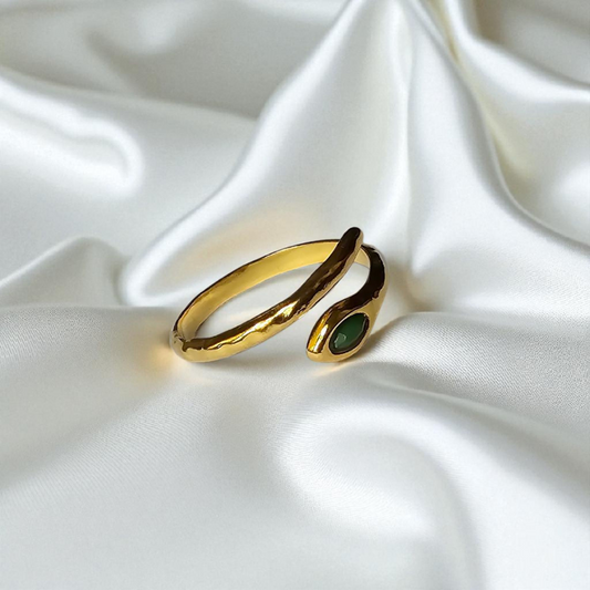 Elegante anillo dorado con detalle verde esmeralda.